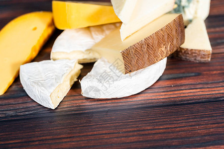 深色木制背景上的各种大美食奶酪楔子背景图片