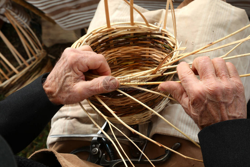 在市场上编织柳条筐的老工匠的手图片