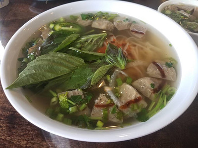 碗热的越南面条汤配有肉丸蔬菜图片