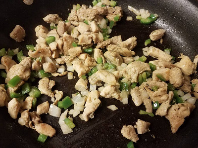 用洋葱和青椒在煎锅里烹饪火鸡肉图片