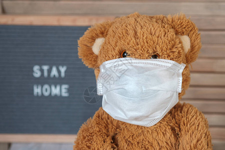 灰色毡板上戴着医用口罩的可爱泰迪熊图片