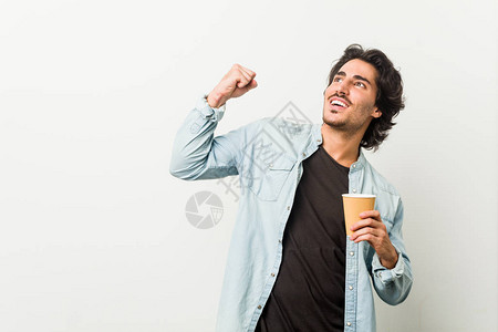 年轻酷男在胜利后喝着咖啡举起拳头图片
