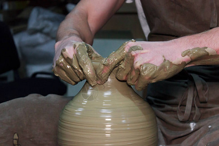 有经验的陶器匠在陶器轮子上做一个大的花瓶图片