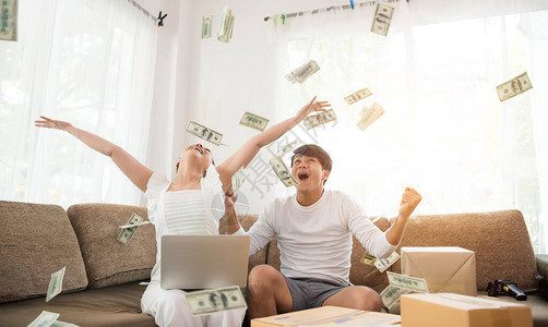 快乐的情侣在金钱雨下欢笑成功坐着图片