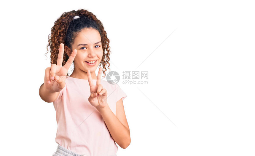 穿着便衣的漂亮的卷发女孩微笑着看摄影机手指在做胜利标志图片