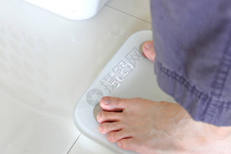 赤脚站在天平上与人在体重秤上测量公斤的减肥概念体重秤图片