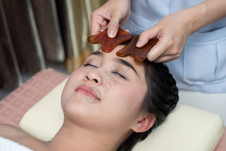 亚洲年轻女在亚洲接受面部刮痧治疗图片