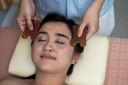 亚洲年轻女在亚洲美女接受面部刮痧治疗背景图片
