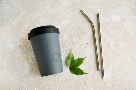 米色背景上可重复使用的环保可持续方便竹杯和不锈钢金属吸管图片