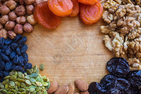 在木制厨房板上葡萄干李子杏干不同品种的坚果素食特殊饮食健康食品图片