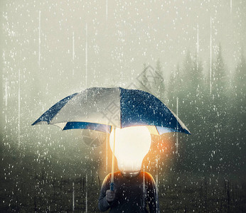 有灯泡而不是头在下雨时拿着伞的男人积极的心态观念概图片