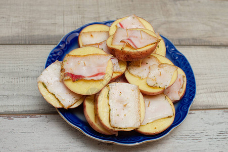 培根烤土豆关闭猪油焗土豆切成两半的烤土豆片配切碎的培根和香料美食摄图片