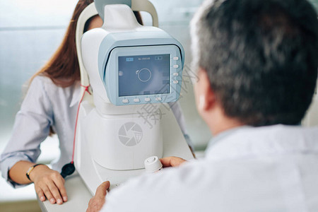 在检查年轻女专家的视力时使用现代设备的眼科医生图片