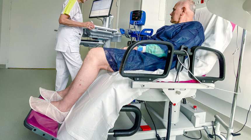 坐在法国现代医院现代医疗椅上的老年男在感染冠状乐观看法和护士准图片