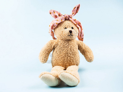 泰迪熊带着粉红花束头带耳朵是蓝底背景图片
