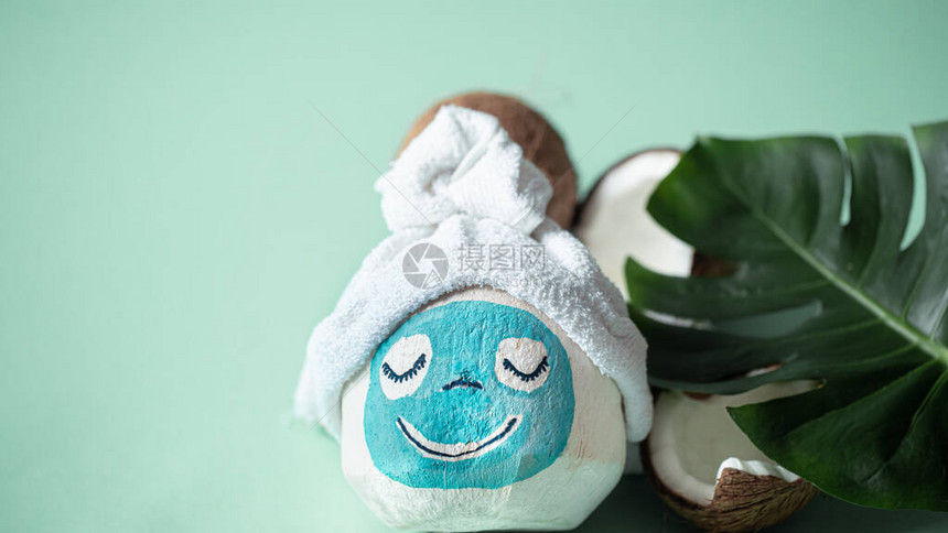 创意水疗概念顶部有面罩和毛巾的椰子带有热带龟背竹叶子在蓝色背景上复制空间温泉平躺美容水疗和个图片