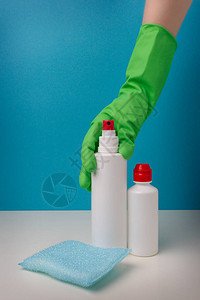 手持保护绿色手套将蓝色背景的抗消毒剂图片