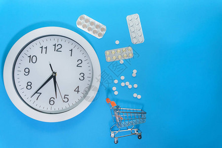 蓝色背景上的药品和钟表购物车购买药丸和药品图片