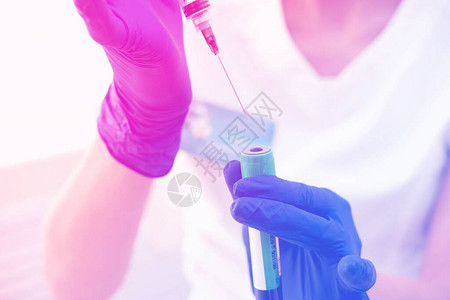用于医疗注射的注射器在手上戴着蓝色手套护士或医生液体药物图片