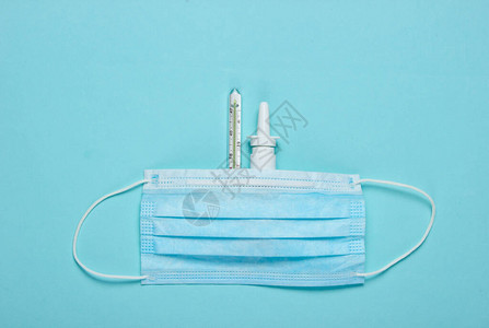 蓝色背景下的医学静物医用口罩温度计鼻喷雾剂极简主义图片