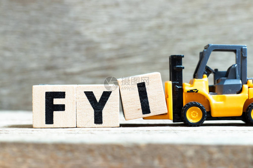 玩具叉车Toyfrklift持有关于木材背景的字母块I图片