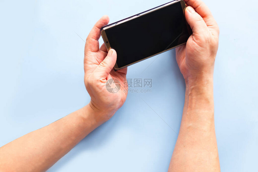 男子持有黑色屏幕模拟电话以蓝色背景图片