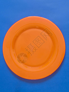 蓝色背景上的空橙色盘子图片