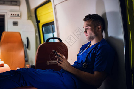 年轻的医护人员坐在救护车里带着他的图片
