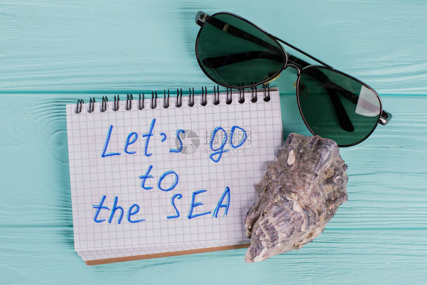 旅行概念由蓝色背景的海壳和太阳眼镜组成让我们去海洋写在笔记本上创用极图片