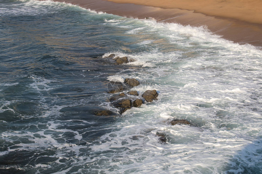 在水中的岩石将随着海岸的波浪断图片