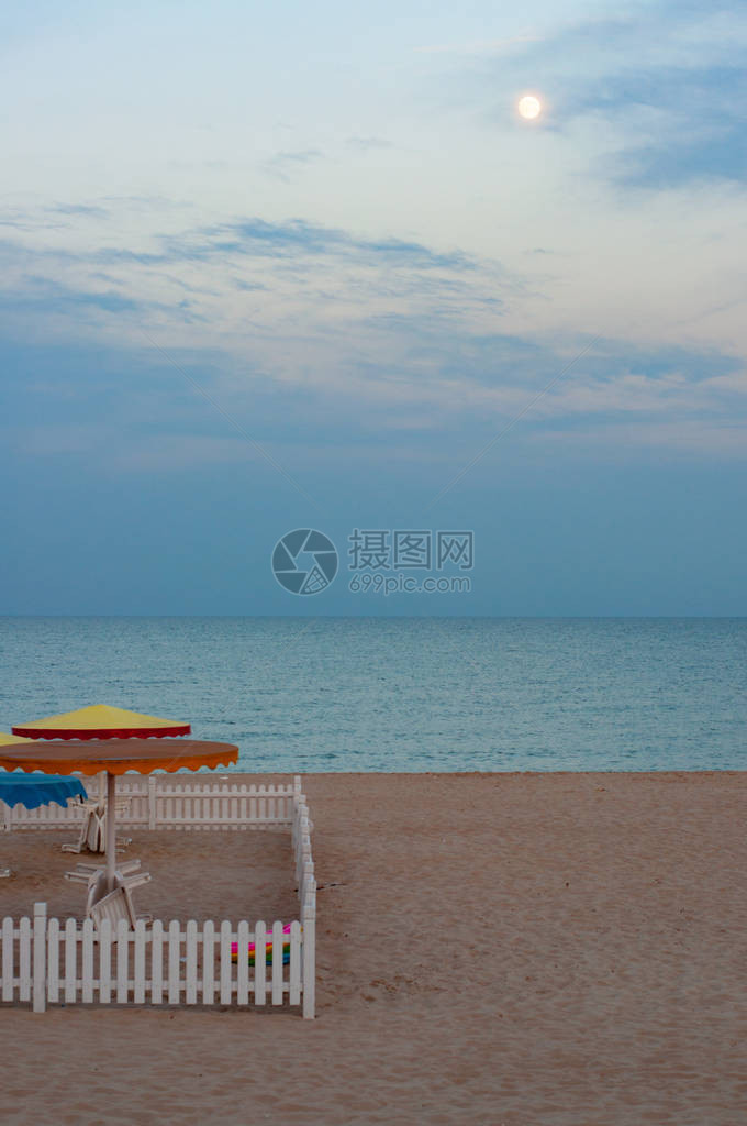 海滩沙子上的白色木栅栏广场与昏暗的夏季海景背五颜六色的沙滩伞和平静的海水地平线在黑海岸的海上度假风景最图片