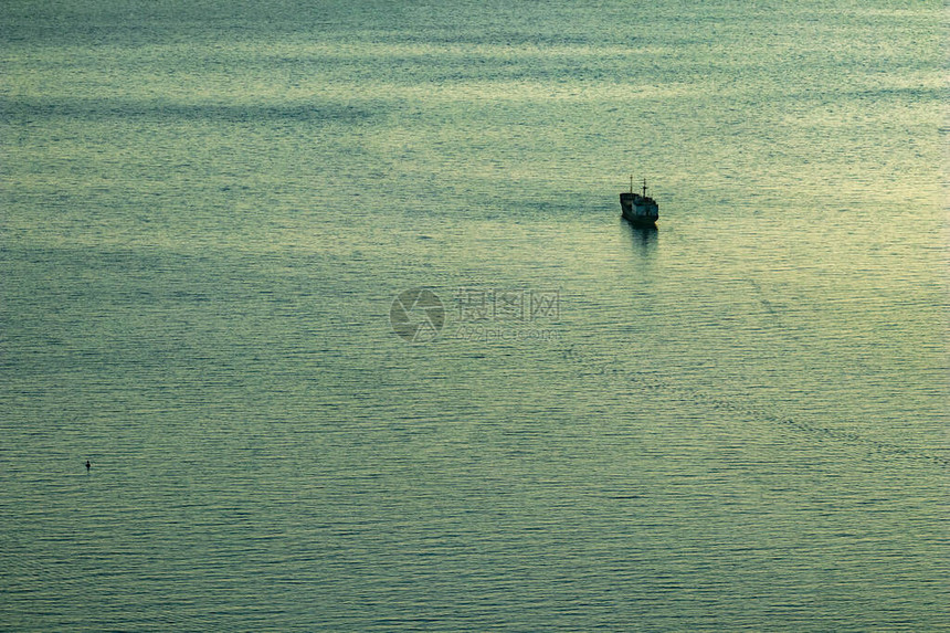 一艘集装箱货运船在阿尔巴尼亚萨兰达镇附近的蓝色小时海水中航行的剪影图片