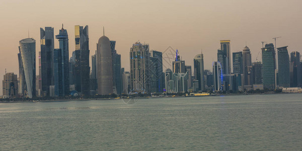 卡塔尔多哈日光天线显示阿拉伯湾与现代摩天大楼树木云彩和天图片