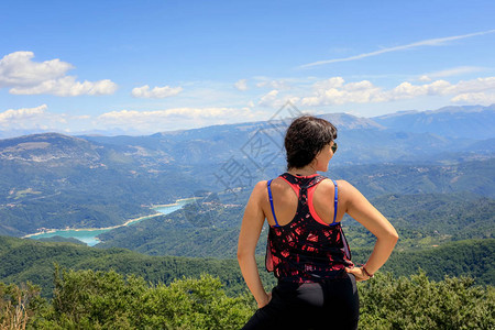 山中隐身的女孩在山上探究地平线山谷和下湖的风景在一个图片