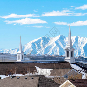 广场上的现代教堂有陡峭的雪山和阳光灿烂的蓝天背景图片