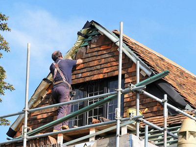中年工人站立在脚手架上把搭配的屋顶瓷砖图片