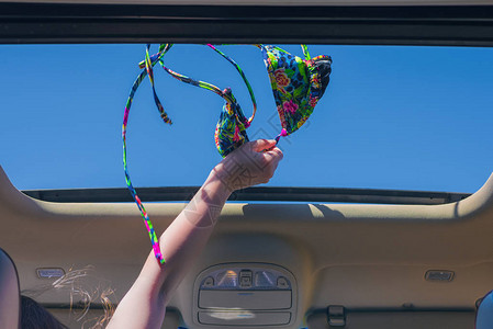 女孩将比基尼胸罩从车辆的敞开式舱口中甩掉旅行生活方式概念图片