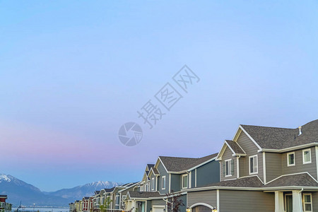 在日落时山顶和天空上建有高地和山谷屋顶的住宅图片