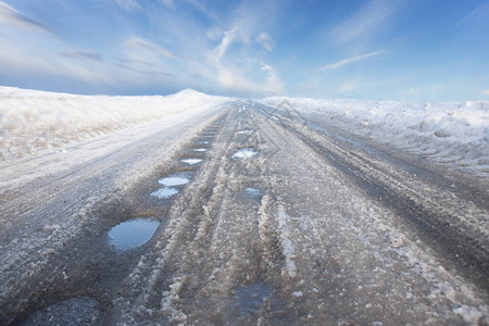 早期北欧春天农村公路有坑洞和融雪蓝图片