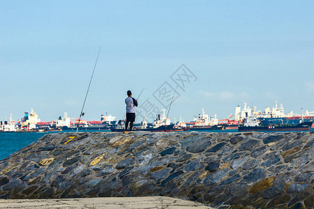 在新加坡船舶锚对面的水坝上渔民在海上图片