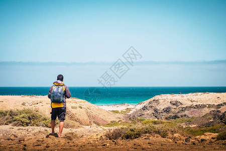站立的背包客男子看着海滩和海岸的背影图片
