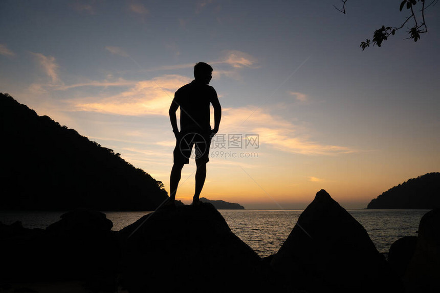 自由人站在泰国苏林美丽的岛屿海滩岸的岩石上图片