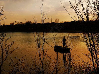 日落时在湖边的船上站着一图片