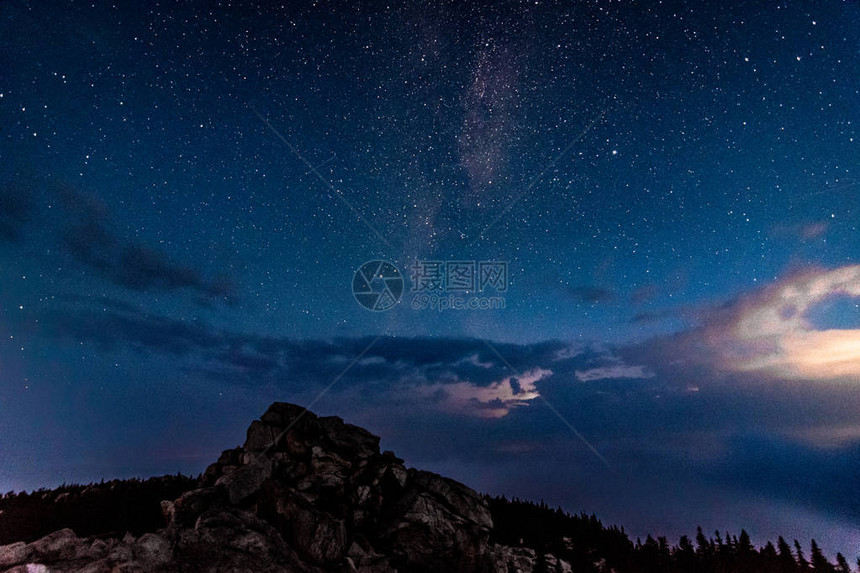 夜空中的银河系在落基山和风雨如磐的云层之上图片