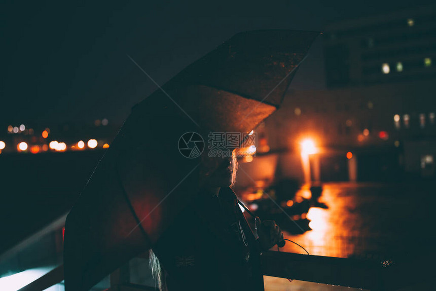 在夜街的雨伞下站在路边的美丽年轻孤图片