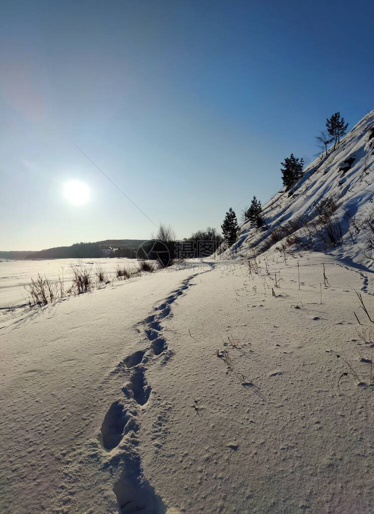 在冰冻的河流和斜坡附近美丽的纹理雪地上留下深的人类脚印图片