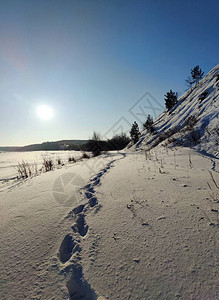 在冰冻的河流和斜坡附近美丽的纹理雪地上留下深的人类脚印图片