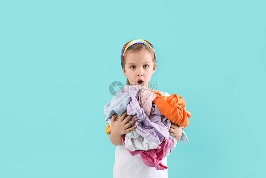 惊讶的小女孩在彩色背景上有脏衣服图片