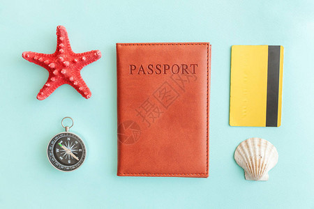 最简单便的公寓内装有护照指南针金信用卡和蓝糊彩色潮流背景的贝壳图片