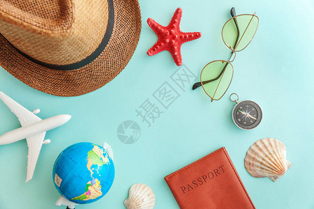 最简便的平铺有飞机护照太阳镜全球帽子罗盘和蓝糊彩色潮流背景的贝壳图片